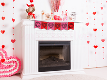 Load image into Gallery viewer, Close-up of a Valentine’s Day banner hanging on a white fireplace mantle, surrounded by heart-shaped decorations and Valentine's Day-themed items.