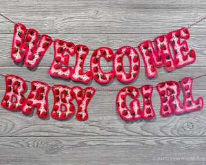 Welcome baby girl banner with pink and purple conversation heart pattern letters, adorned with hearts. A joyful celebration of a new arrival.