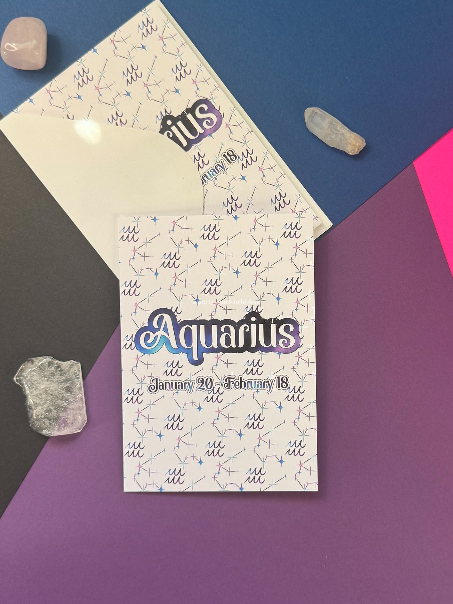 An Aquarius zodiac card set displayed on a geometric background of blue, purple, and pink. The cards feature a white background with a light blue constellation pattern and the word 'Aquarius' in stylized purple and blue lettering.